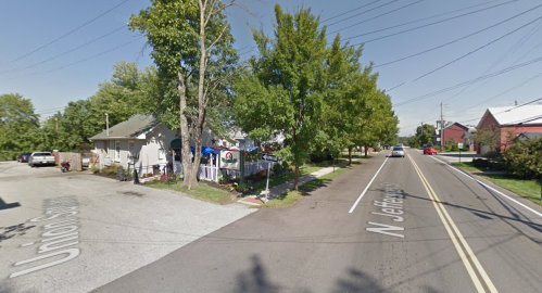 A street view showing a residential area with trees, houses, and parked cars along N Jefferson Street.