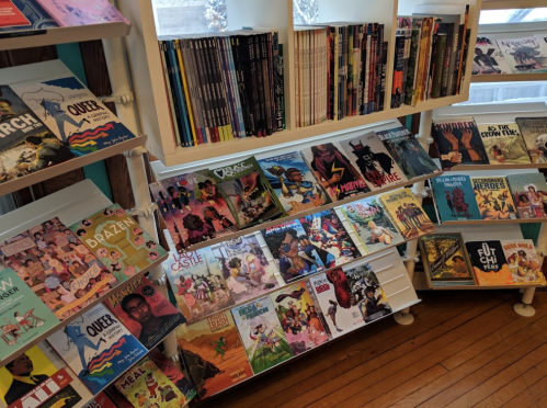 A colorful display of graphic novels and comics on shelves in a bookstore, featuring diverse titles and artwork.