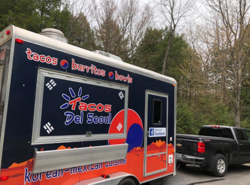 A food truck named "Tacos Del Seoul" offers Korean-Mexican cuisine, parked in a wooded area.