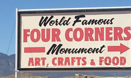 Sign for "World Famous Four Corners Monument" featuring art, crafts, and food, with directional arrow.
