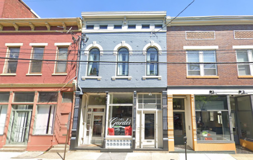 A row of colorful storefronts, featuring a blue building with arched windows and a sign that reads "Del Cardo's."