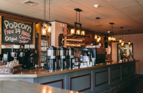 Cozy café interior with a popcorn sign, coffee machines, and warm lighting. A welcoming atmosphere for patrons.