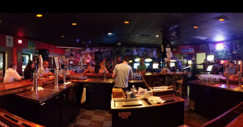 A lively bar scene with patrons at the counter, colorful graffiti on the walls, and various arcade games in the background.