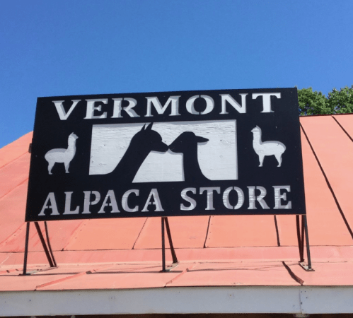 Sign for "Vermont Alpaca Store" featuring silhouettes of an alpaca and a goat against a blue sky.
