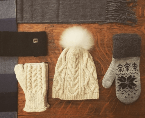 A cozy winter flat lay featuring a knitted hat, gloves, and a scarf on a wooden surface.