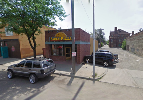 A small pizza shop named "Paul's Pizza" with an open sign, surrounded by parked cars and a quiet street.