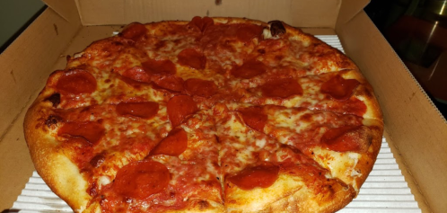 A large pepperoni pizza in a cardboard box, with melted cheese and crispy crust.