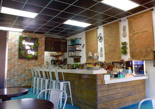 A cozy café interior featuring a wooden counter, menu boards, and modern seating in a bright, inviting atmosphere.
