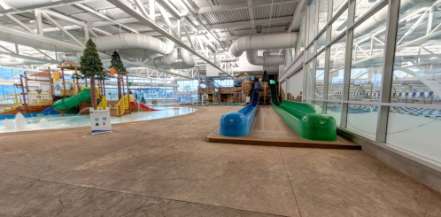 Indoor water park featuring colorful slides, a play area, and a pool with large windows and a bright atmosphere.