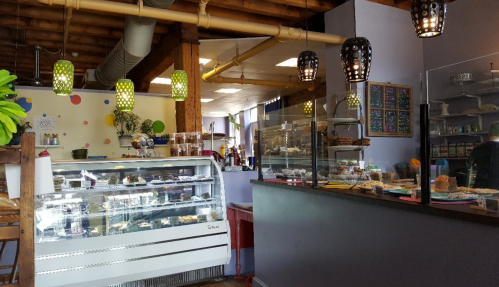 Cozy café interior with a display case of pastries, colorful decor, and pendant lights hanging from the ceiling.