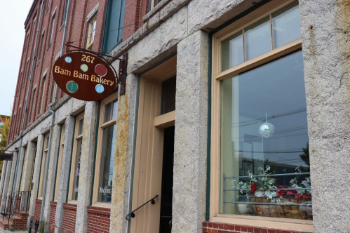 Exterior of Bam Bam Bakery, featuring a sign and large windows with decorative displays.