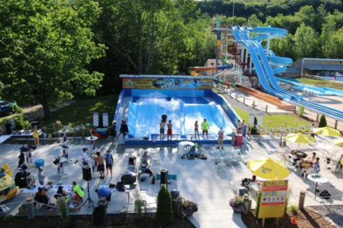A vibrant water park scene featuring a wave pool, water slides, and people enjoying the sun and activities.
