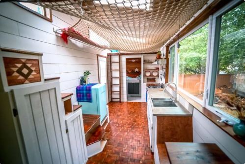 Cozy interior of a tiny home kitchen with wooden accents, a sink, and a netted ceiling for a unique touch.