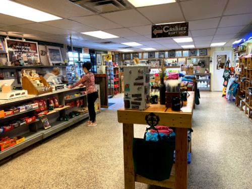 A cozy gift shop interior with shelves of merchandise, a cashier area, and a customer browsing.