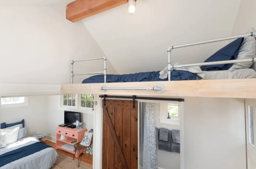 Cozy interior of a small space featuring a lofted bed, a lower bed, and rustic wooden accents.