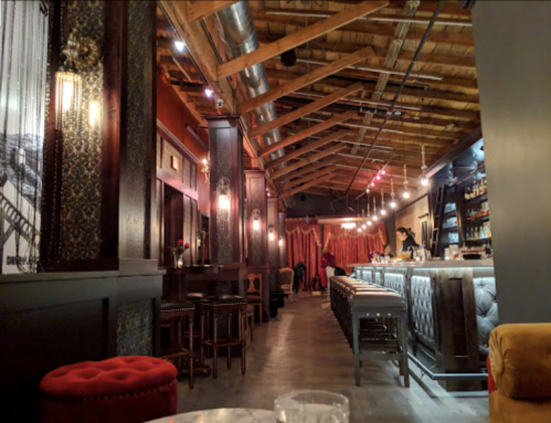 A stylish bar interior with wooden beams, plush seating, and a well-lit counter, creating a cozy atmosphere.