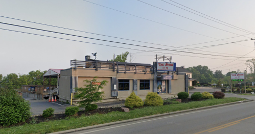 A building with a sign reading "The Show," featuring outdoor seating and surrounded by greenery along a road.