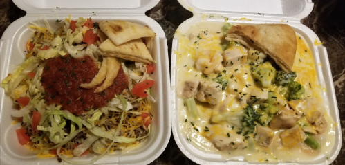 Two takeout containers: one with a salad topped with salsa and tortilla chips, the other with creamy chicken and broccoli.