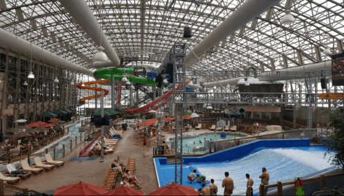Indoor water park featuring slides, a wave pool, and lounging areas, bustling with visitors enjoying the attractions.