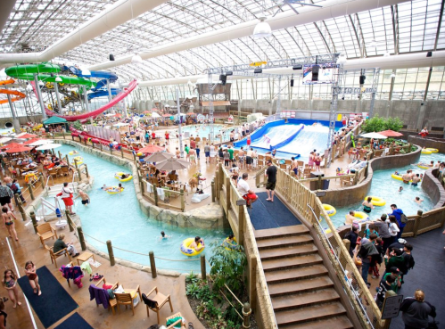 Indoor water park featuring slides, a wave pool, and numerous visitors enjoying various water activities.