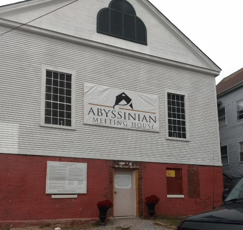 Exterior of the Abyssinian Meeting House, featuring a large banner and historical information on the wall.