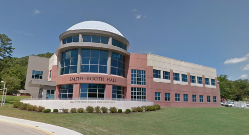 Modern building with a dome roof, labeled "Smith-Booth Hall," surrounded by greenery and a paved pathway.
