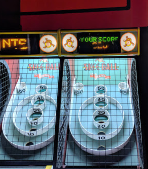 Two skee ball lanes with scoreboards displaying points and "YOUR SCORE" above them.