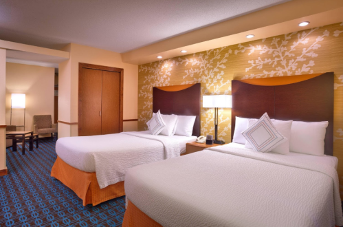 A cozy hotel room featuring two beds, a wooden wardrobe, and warm, inviting decor with soft lighting.