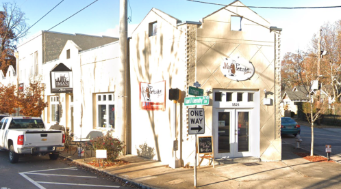 A street view of a building with multiple storefronts, including "IMAS" and "Mia Petatar," on a sunny day.