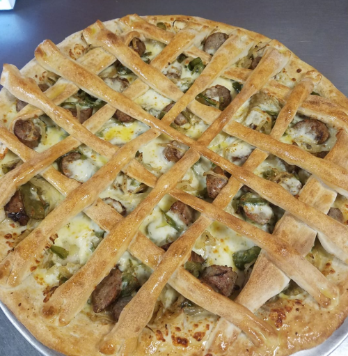 A freshly baked pizza topped with sausage, green peppers, and a lattice crust.