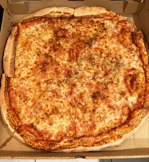 A large cheese pizza in a cardboard box, with a golden crust and a sprinkle of herbs on top.