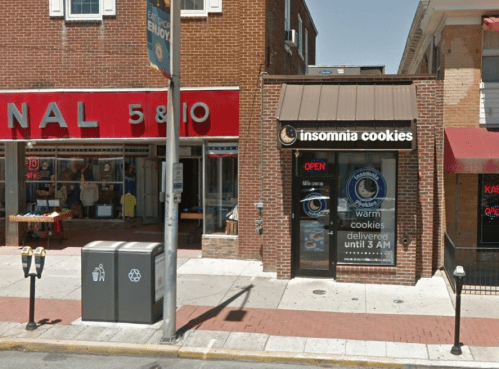A street view of a brick building with an "Insomnia Cookies" shop and a red storefront next door.