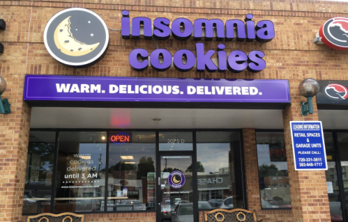 Exterior of Insomnia Cookies shop with a sign that reads "Warm. Delicious. Delivered." Open until 3 AM.