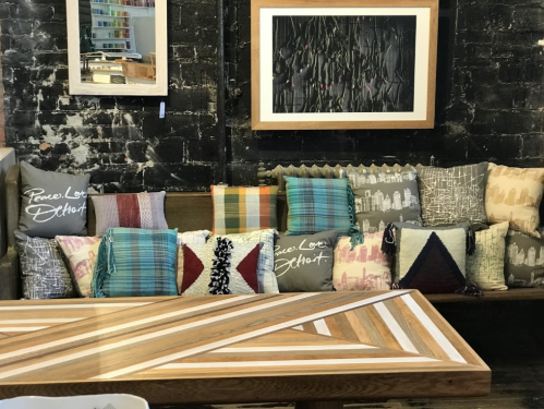 A cozy seating area with a variety of decorative pillows on a wooden bench and a patterned table in front.