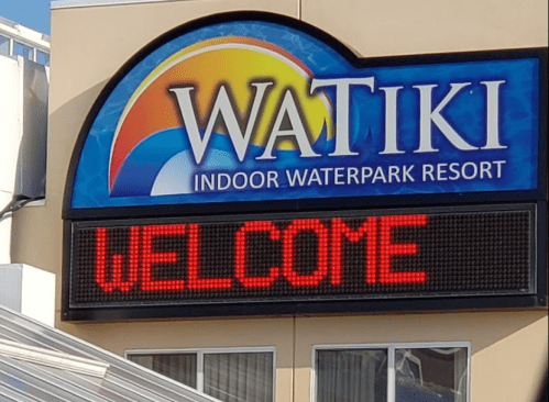 Sign for Watiki Indoor Waterpark Resort displaying "WELCOME" in bright red letters.