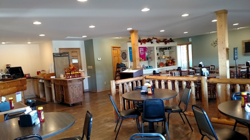 Cozy restaurant interior with wooden tables, chairs, and a counter, featuring warm lighting and autumn decorations.