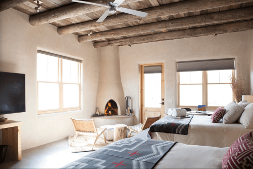 Cozy room with two beds, a fireplace, and rustic decor, featuring wooden beams and natural light.