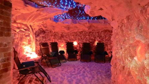 A cozy salt cave with reclining chairs, illuminated by soft blue and orange lights, creating a relaxing atmosphere.