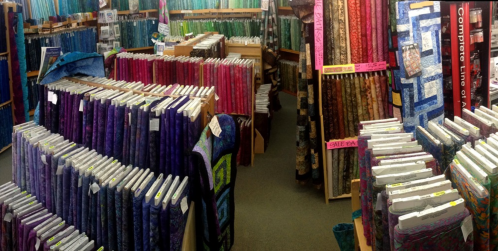 A vibrant fabric store filled with colorful rolls of fabric arranged on shelves, showcasing various patterns and textures.