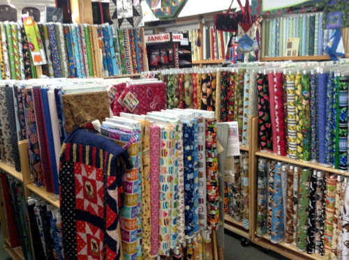 A colorful display of various fabric rolls arranged on shelves in a craft store.
