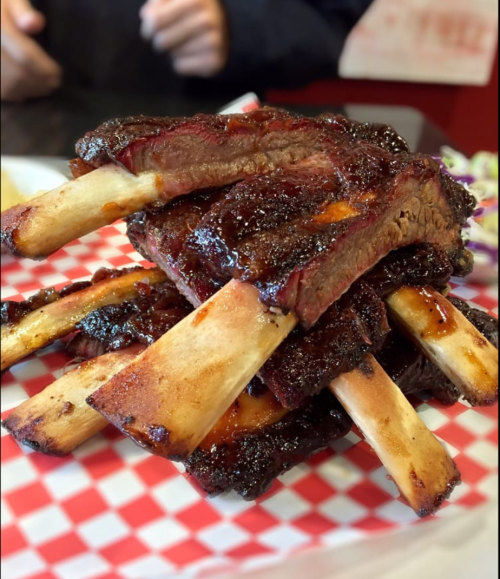 A stack of juicy, glazed ribs on a red and white checkered plate, showcasing tender meat and charred edges.
