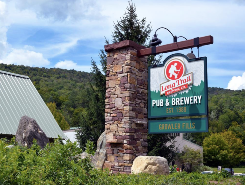 Sign for Long Trail Brewing Co. Pub & Brewery, established 1989, featuring a stone pillar and green landscape.