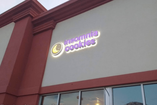 Sign for Insomnia Cookies on a building exterior, featuring a moon and the brand name in bright neon letters.