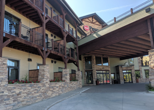 Exterior view of a hotel with stone accents, wooden beams, and balconies, featuring a welcoming entrance.