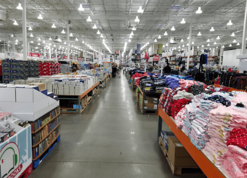 A wide aisle in a warehouse store lined with shelves of books and clothing on either side.