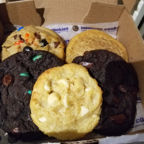 A box of assorted cookies, featuring chocolate chip, oatmeal, and colorful candy-topped varieties.