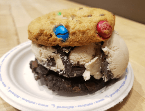 A cookie sandwich with chocolate chip and chocolate cookies, filled with cookies and cream ice cream.