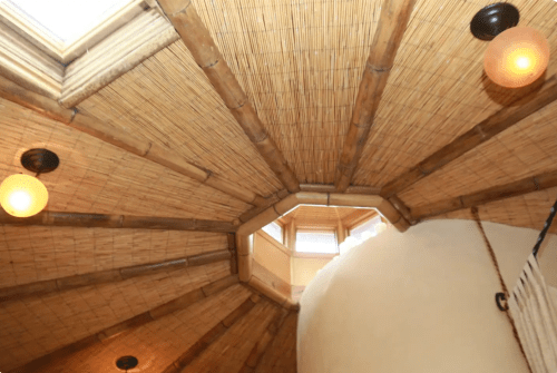 View of a unique ceiling with bamboo beams and round light fixtures, featuring an octagonal skylight.
