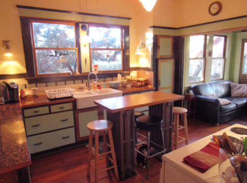 Cozy kitchen with wooden floors, a central island, and large windows letting in natural light.