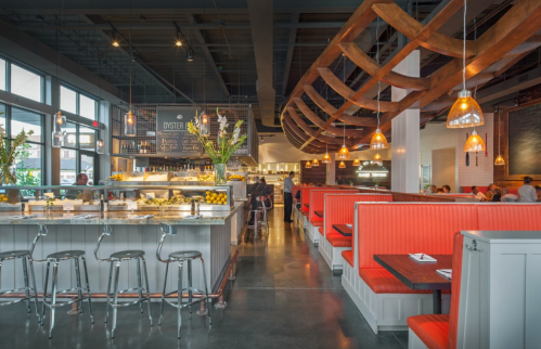 Modern restaurant interior featuring red booths, a seafood display, and warm pendant lighting.
